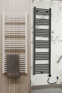 Beli i crni radijator sušač postavljeni u modernim kupatilima, namenjeni grejanju i sušenju peškira